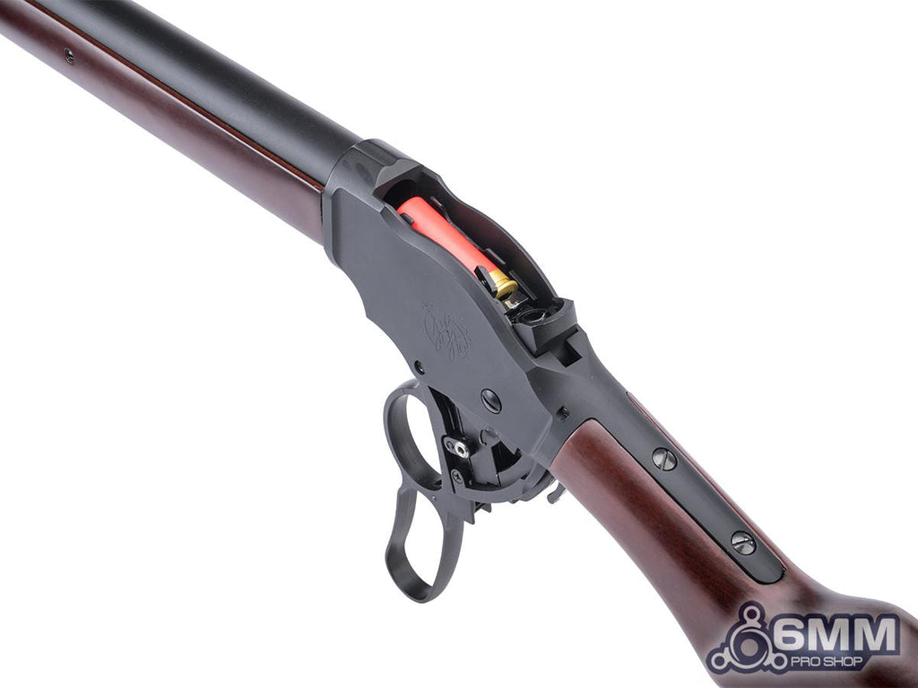 A close-up of a lever-action rifle with a dark brown wood stock and barrel, black metal receiver and trigger guard, and a visible orange-red cartridge inside the magazine, shown on a white background.