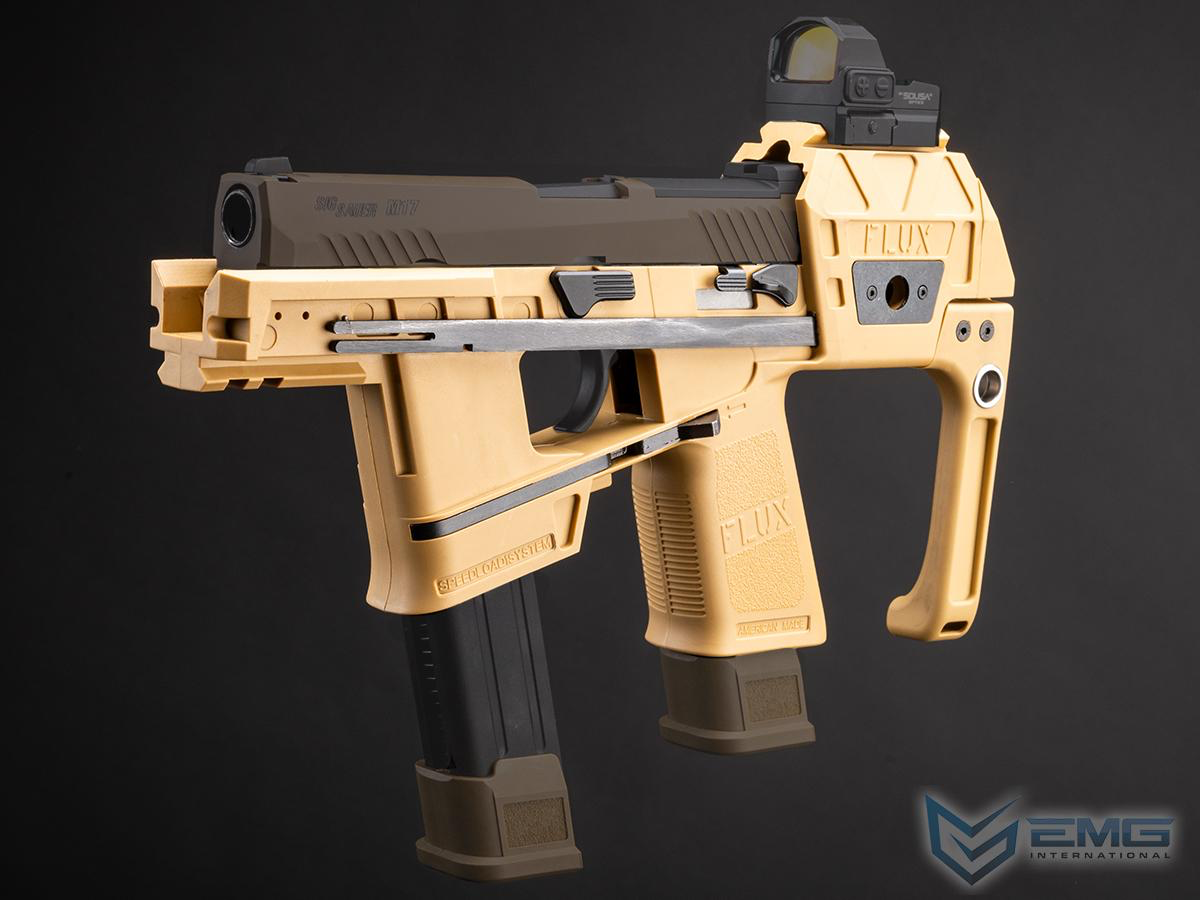 A tactical submachine gun replica in tan and black, featuring a mounted red dot sight and a vertical foregrip, shown against a dark studio background with an EMG International logo in the corner.