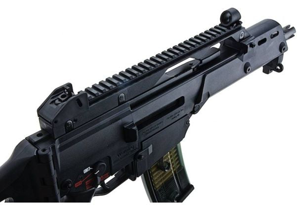 A close-up of a black tactical rifle or airsoft gun with a ridged foregrip, adjustable stock, and a visible green-and-black magazine, shown against a plain white background.