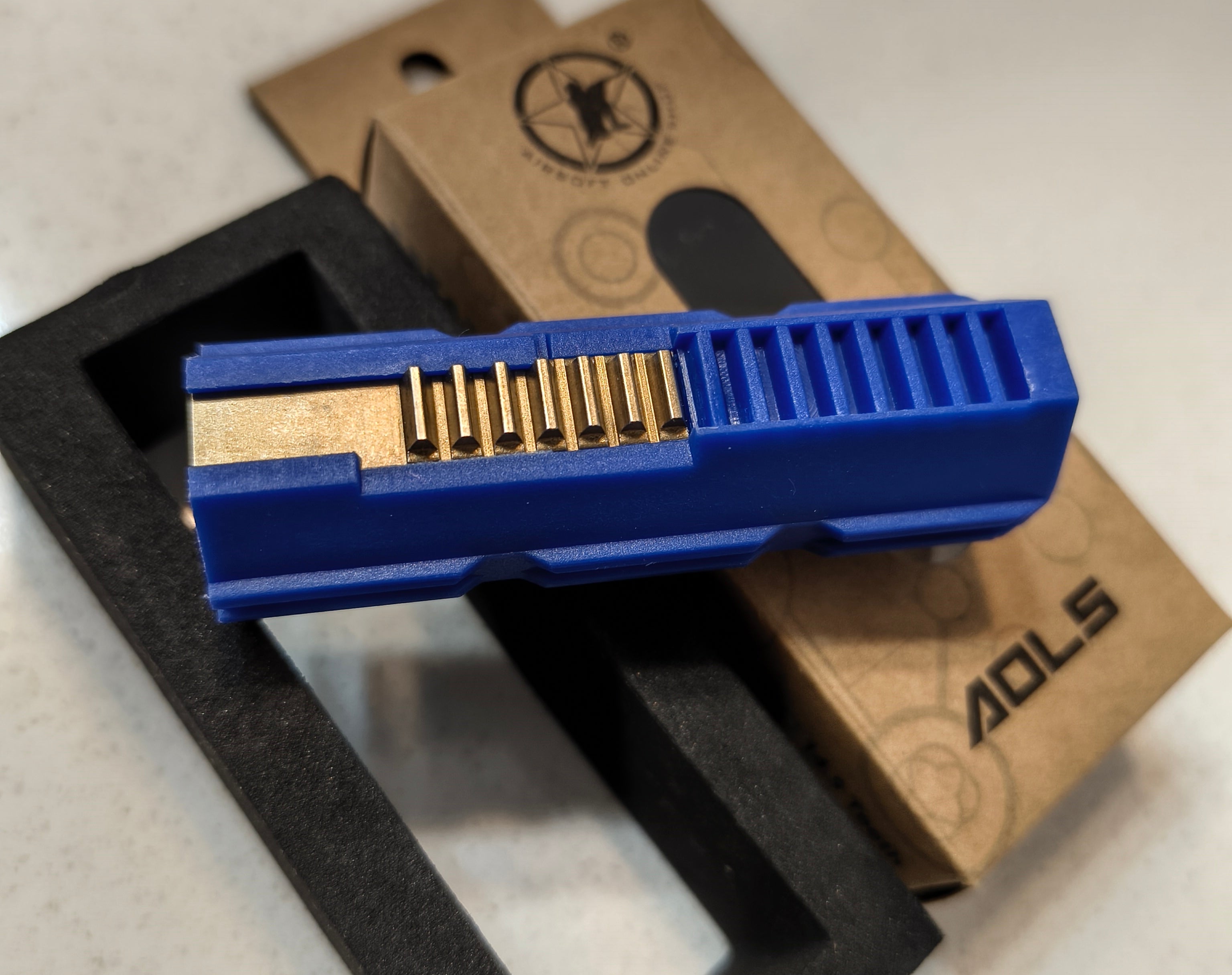 Blue tool with gold interior on a white surface with a brown box labeled 'ADLS'.