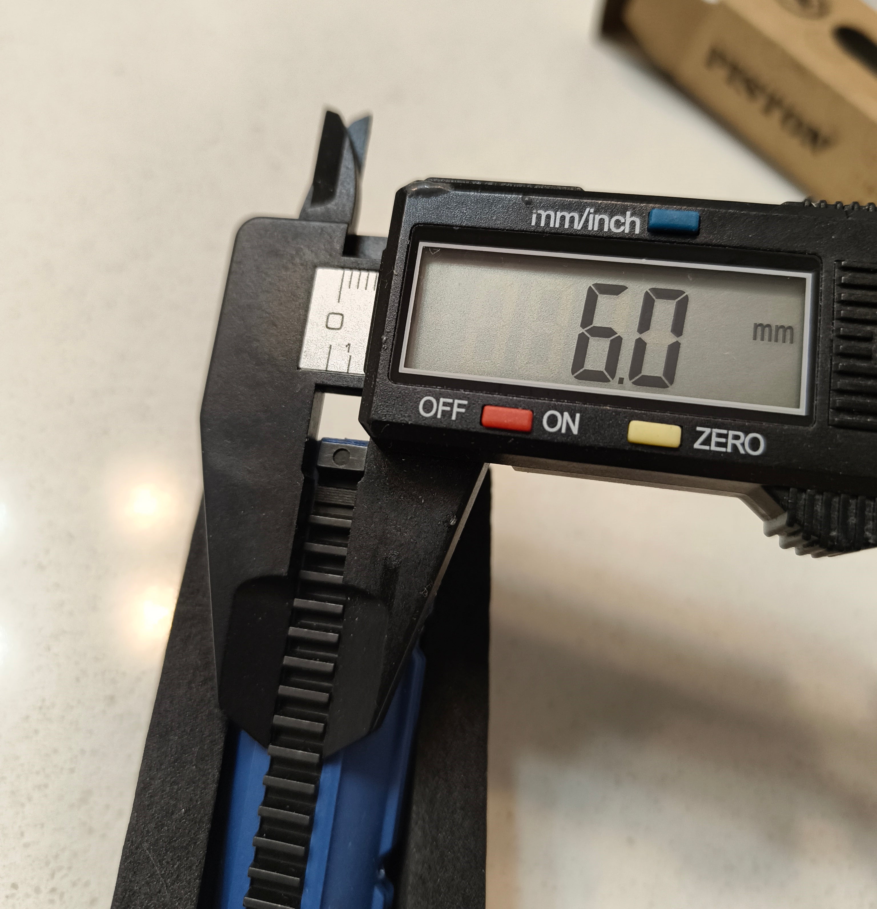 Digital caliper measuring a width of 60mm on a light gray background