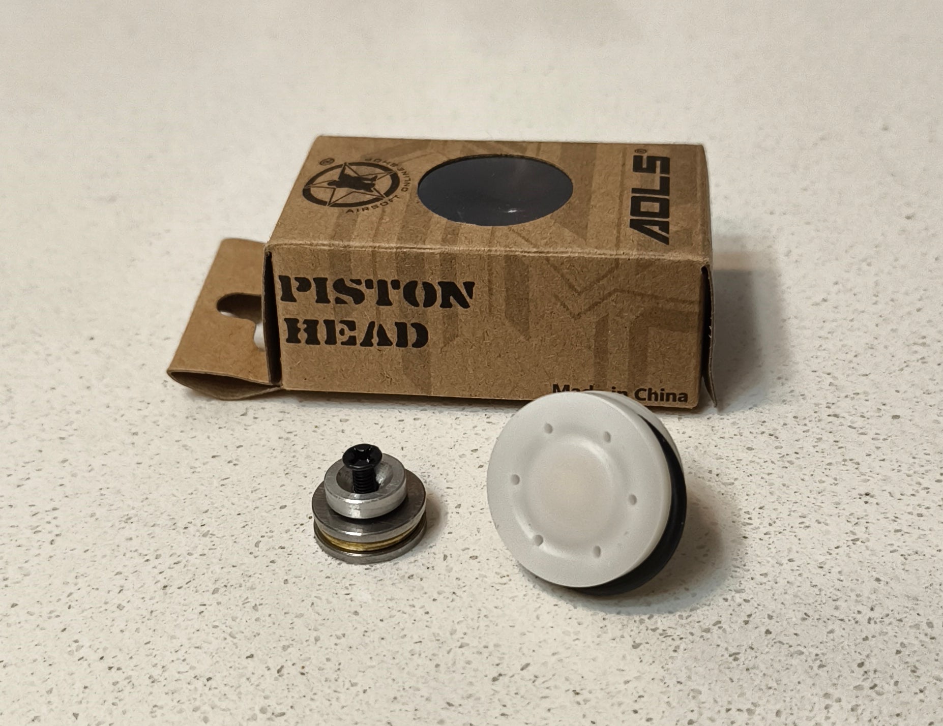 Piston head components and cardboard box on a speckled surface