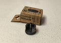 Black cylinder head on a light gray surface with a cardboard box labeled 'Cylinder Head' in the background.