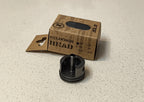 Black cylinder head on a light gray surface with a cardboard box labeled 'Cylinder Head' in the background.