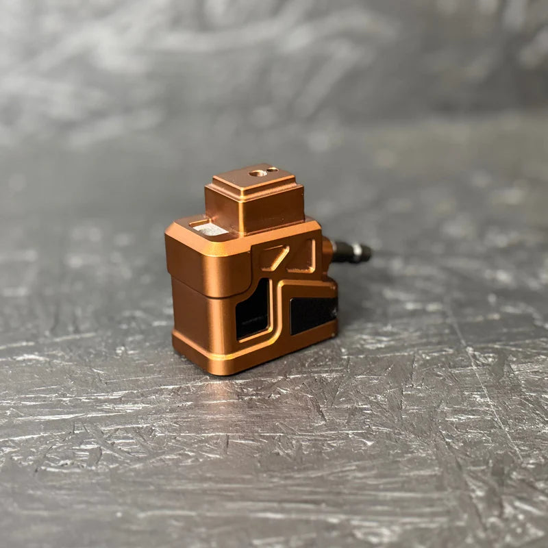 Bronze-colored mechanical component on a gray textured surface