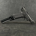 Black handgun with magazine on a gray textured surface
