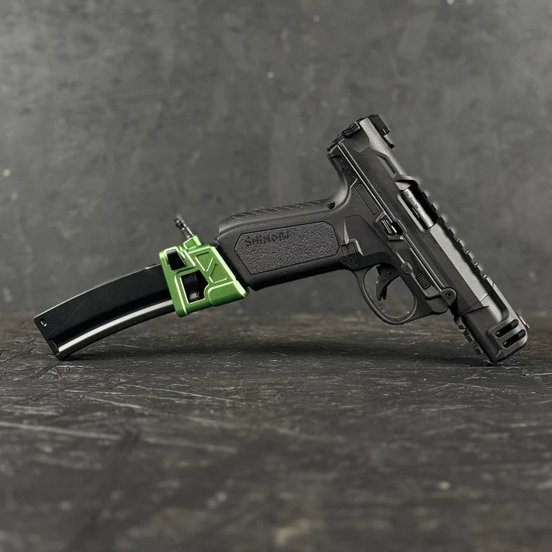 Black handgun with a green component on a dark surface