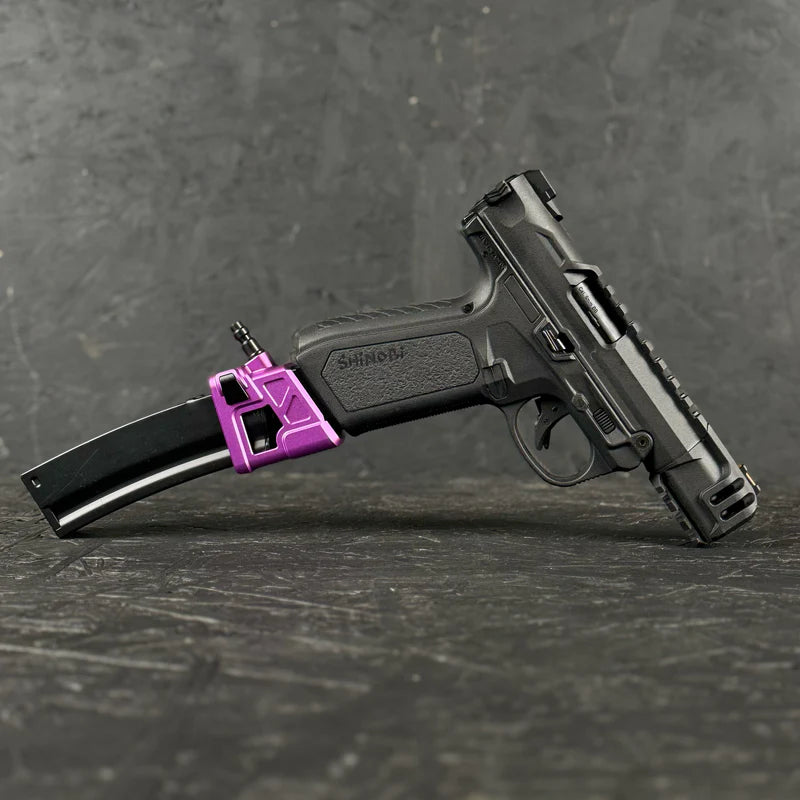 Black handgun with a purple grip on a dark textured surface