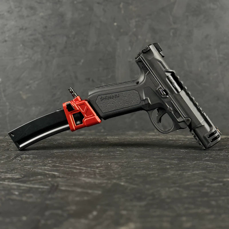Black handgun with a red magazine on a dark surface