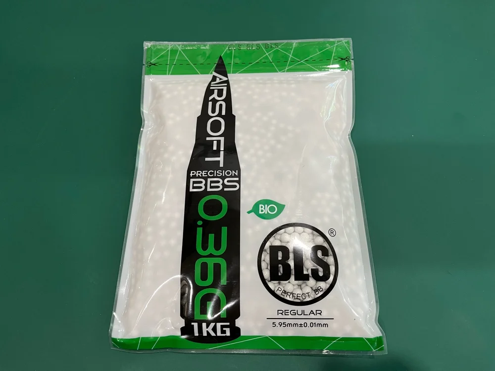 Packaged airsoft BBs with BLS branding on a green background