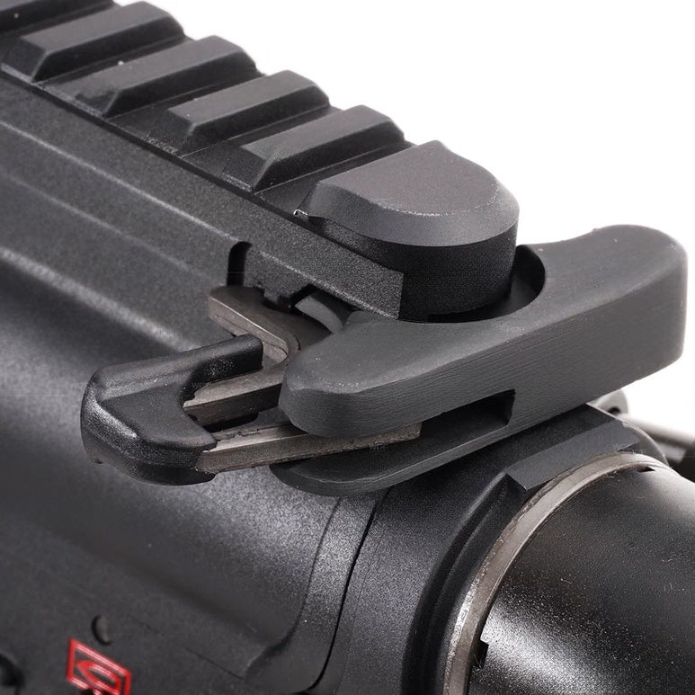 Close-up of a black tactical accessory mounted on a black rail system, showing the latch mechanism and textured surface against a white background.